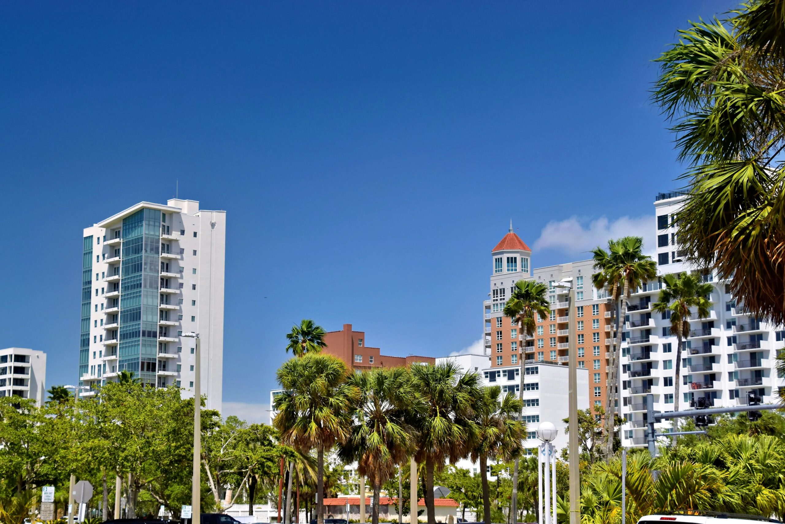 View of modern residential buildings and palm trees in a sunny Florida neighborhood. Ideal for local land buyers, real estate investors, and those selling land in South Florida.